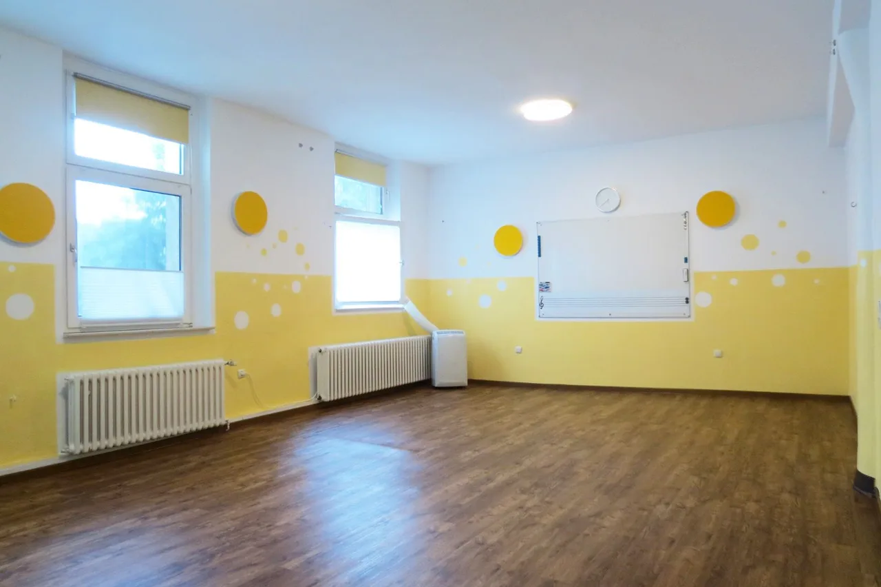 Der helle Kursraum in Essen-Steele mit türkisfarbener Wand und gelben Stühlen